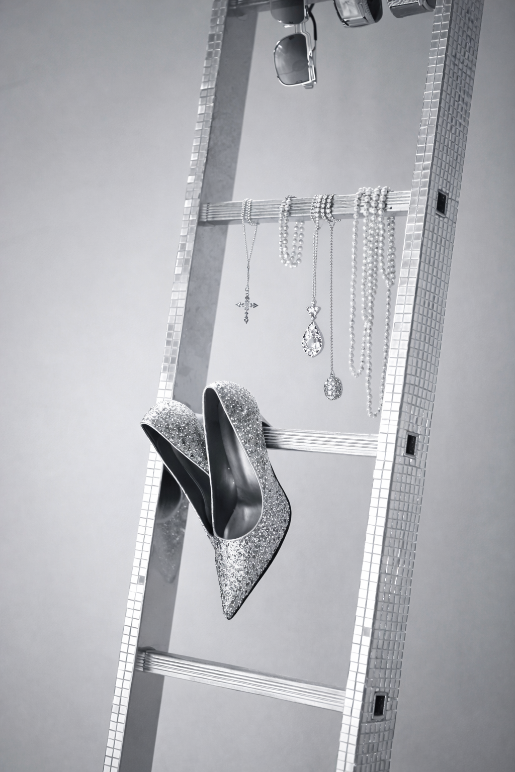 Styling view of a pear-shaped cubic zirconia pendant necklace in silver tone, hanging alongside other jewelry pieces on a decorative ladder display.