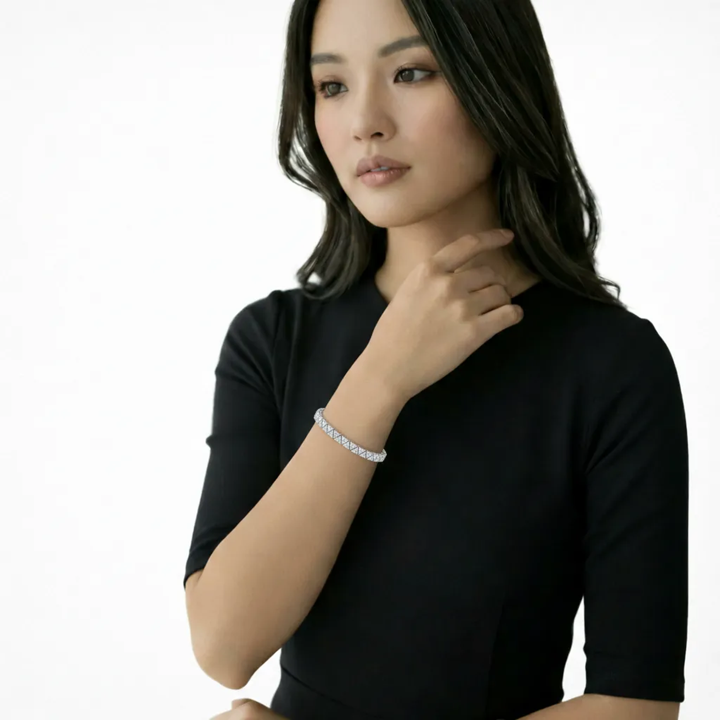 Model shot highlights a silver tone cubic zirconia bracelet built from repeating pyramid links paved in stones, wrapping the wrist above a black dress for modern sparkle.