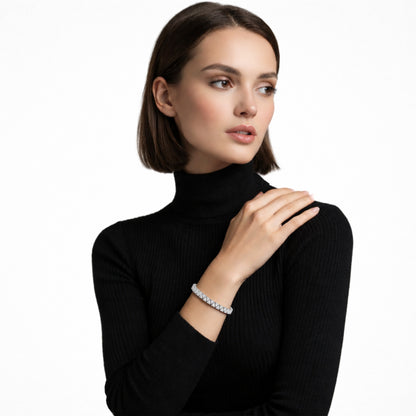 Model view highlights a structured silver tone tennis bracelet built from square cubic zirconia links, stacked over a black ribbed turtleneck for sharp, high-contrast glow.