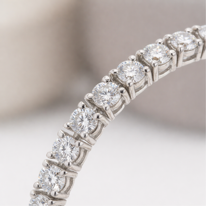 Close up view of round cut cubic zirconia stones set in a continuous silver tone tennis bracelet, highlighting the precise prong setting and brilliant sparkle.