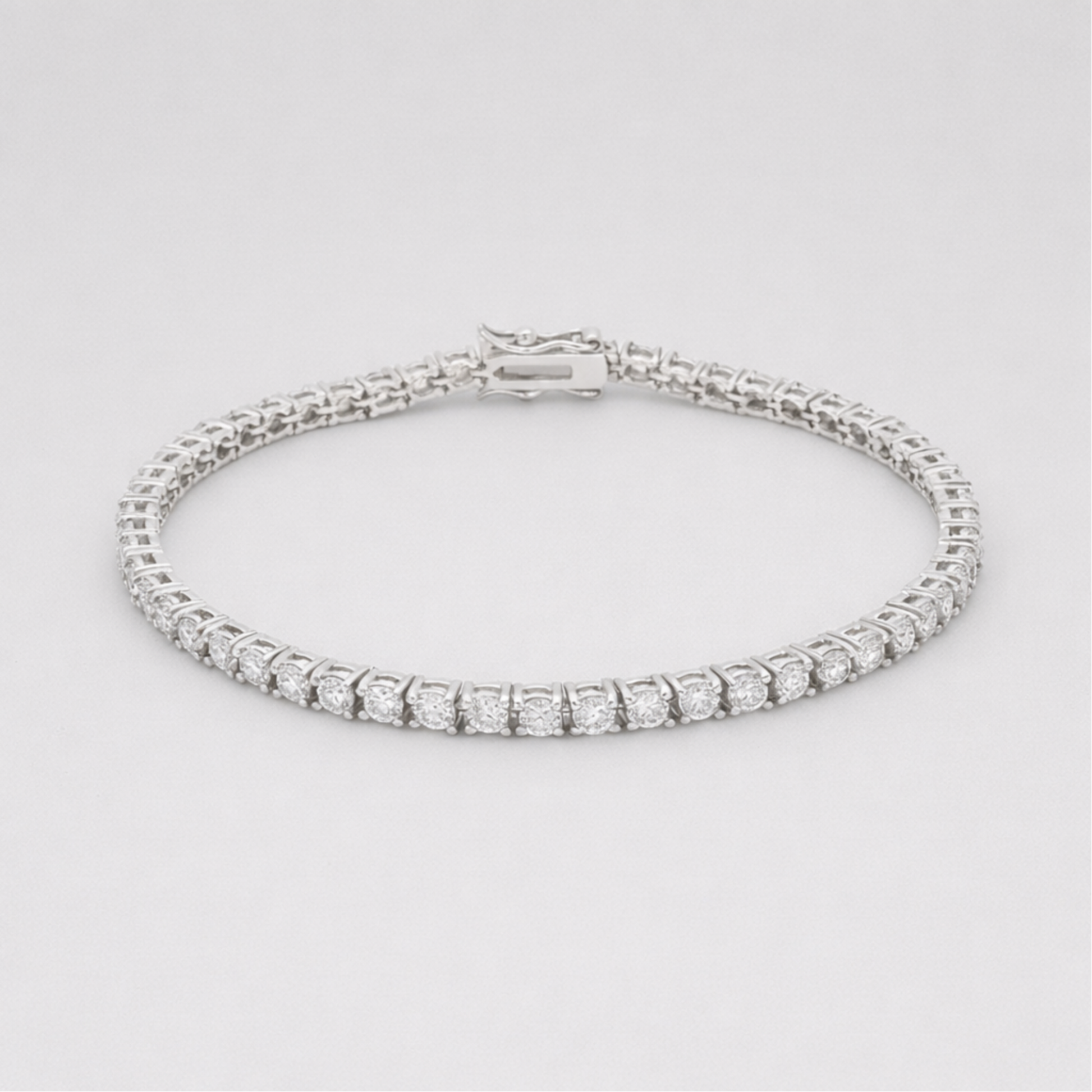 Studio view of a classic silver tone tennis bracelet featuring a continuous row of round cut cubic zirconia stones and a secure box clasp closure.